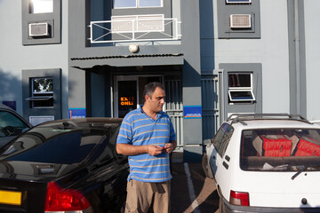 man waiting in the outdoors parking in an commercial area in front of a shop