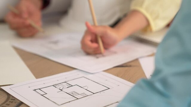 Architect and safety engineer discussion about building blueprint displaying on laptop on table with architectural document and wooden block scatter around at modern office. Closeup. Delineation.