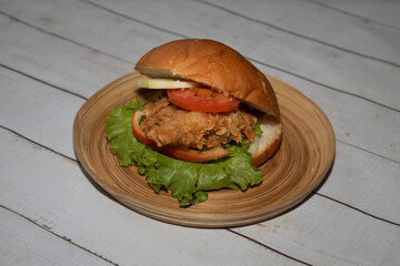 Classic Chicken burger with tomato, lettuce and cucumber served in dish isolated on napkin...