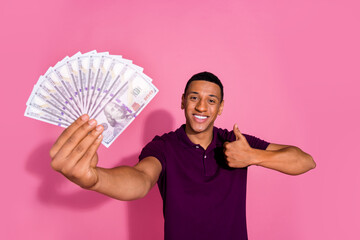 Photo of attractive young man hold money fan thumb up dressed stylish violet clothes isolated on...