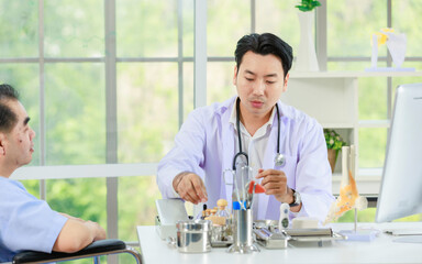 Asian smart man, orthopedic doctor consulting elderly patient with leg injury explaining treatment methods of trauma using anatomical model foot. Treatment of embitterment, fracture of leg in hospital