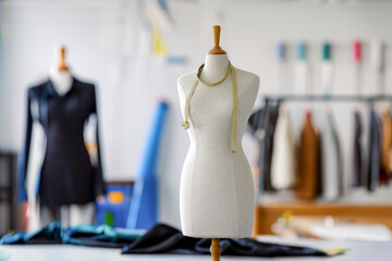 Fashion dummy with a measure tape, tailor atelier in the background