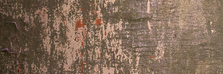Peeling paint on the wall. Panorama of a concrete wall with old cracked flaking paint. Weathered rough painted surface with patterns of cracks and peeling. Wide panoramic grunge texture for background