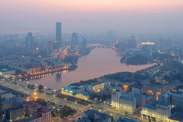 Top view of the city of Yekaterinburg, Sverdlovsk region, Russia. Beautiful cityscape. Aerial view of the City Pond, streets, buildings and skyscrapers. Evening twilight and haze.