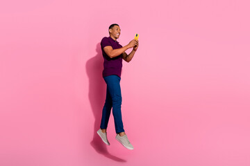 Full length photo of nice young male jump hold telephone dressed stylish violet garment isolated on pink color background