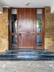 A classic design house entrance with a wooden door between glass openings. Travel to Athens, Greece.