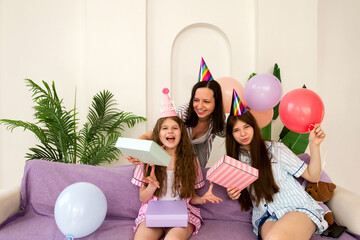 Joyful birthday celebration with mother and daughters opening gifts.