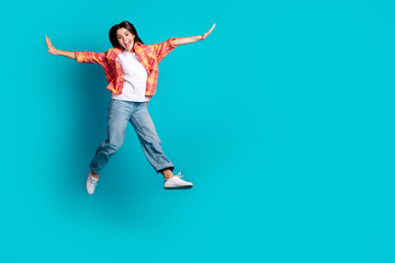 Full size photo of nice young girl jump fly empty space wear plaid shirt isolated on teal color...