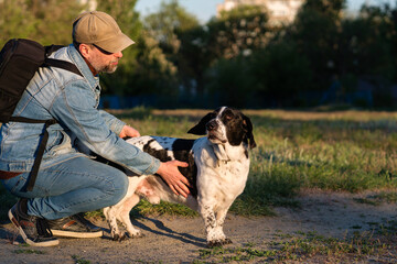 Man and hound dog in touching moment at sunset.