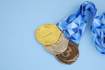 Three medals - gold, silver and bronze with blue ribbon on blue background.