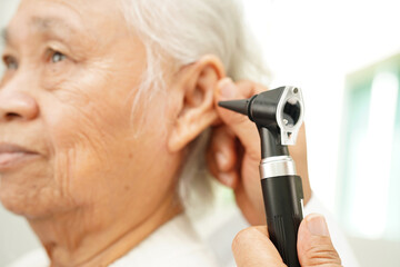 Otolaryngologist or ENT physician doctor examining senior patient ear with otoscope, hearing loss...