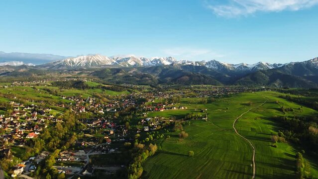 Aerial view of Tatra mountains and Zakopane town at sunset. Panoramic landscape with mountain ranges and green valleys near village. View on Giewont, Poland