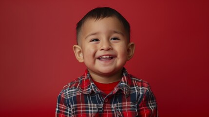 A young boy beams brightly against a vibrant red backdrop