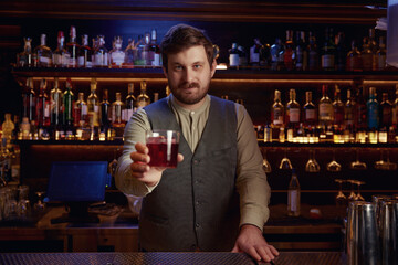 Bartender giving freshly prepared cocktail, closeup view on hand with glass