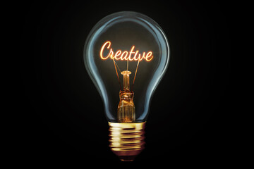 Creative light bulb with a spiral Creative glows on a black background, concept. Thought generator,...