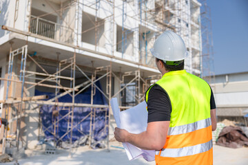 Construction Worker Reviewing Blueprints at Building Site