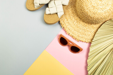 Top view of straw hat, slippers, sunglass and dried palm leaf on colorful background. Summer...