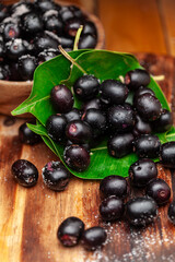 Close-up of 'Indian blackberry' or Jamun (Syzygium cumini) fresh fruits, on a wooden background. Front view.