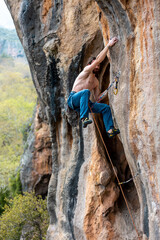 male climber.  strong muscular male rock climber climbs a vertical rock and makes great efforts to...