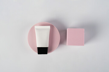 Plastic white tube for cream or lotion. Skin care or sunscreen cosmetic with stylish props on white background.