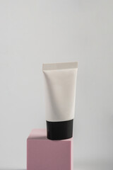 Plastic white tube for cream or lotion. Skin care or sunscreen cosmetic with stylish props on white...