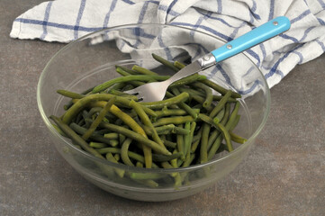 Saladier de haricots verts avec une fourchette et un torchon au second plan