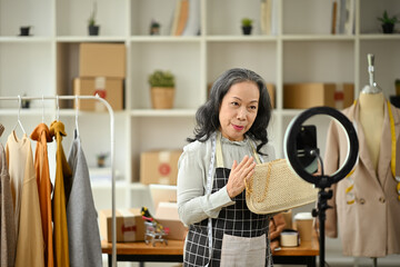 Confident senior business owner live streaming to sale clothes product to customers at her clothing...