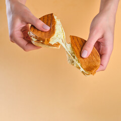 sandwich with cheese in hand on an orange background, stretching cheese