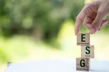 ESG concept.Environmental, Social and Governance.Hand holding wood block with ESG words on green...
