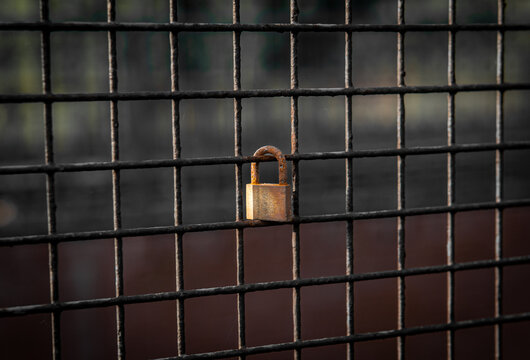 Rusty and aged padlock on a meshed grill from an industrial site representing a romance relationship symbolizing forever love together
