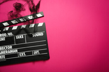 Clapper board and black web on pink background, space for text