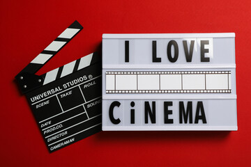 Naklejka premium Light box with text and clapperboard on red background, top view