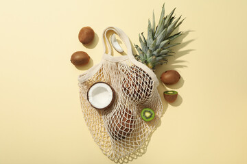Set of tropical fruit in bag on beige background, top view