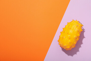 Kiwano fruit on orange and purple background, space for text