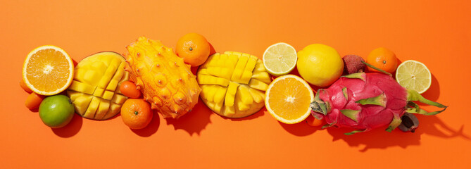 Set of tropical fruit on orange background, top view