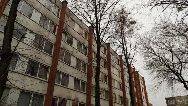 The Soviet-era dormitory building with bare trees. The camera moves forward.