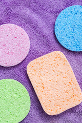 Top view of facial sponges for daily cleansing on purple towel as background