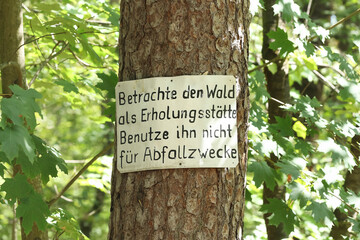 Schild an einem Baum: Betrachte den Wald als Erholungsort. Benutze ihn nicht für Abfallzwecke