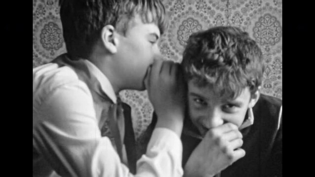Archive film, boy telling secret in friend ear. Trusting relationships between friends in childhood. Secret teenagers communication in Soviet room. Archival black white movies. Retro friendship 1980s