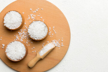 A wooden bowl of salt crystals on a wooden background. Salt in rustic bowls, top view with copy space