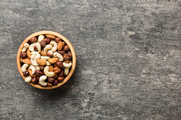 Assortment of nuts in wooden bowl on colored table. Cashew, hazelnuts, walnuts, almonds. Mix of...