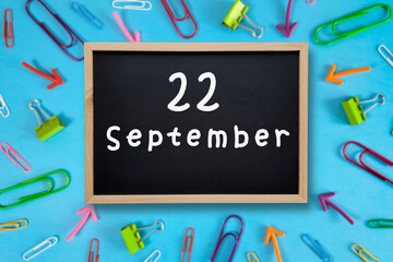 September 22 written in chalk on black board. Calendar date 22th of September on chalkboard on blue...