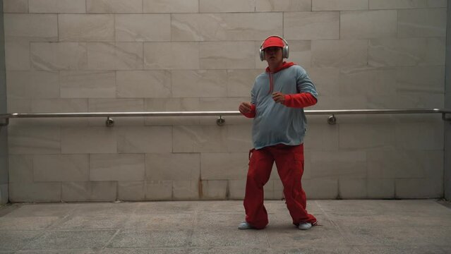 Handsome choreographer practice street dance in gray background. Young attractive b boy dancer perform while wearing stylish cloth. Feeling of lively step. Copy space. Outdoor sport 2024. Sprightly.