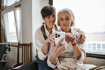 Two women using her phone to take a picture.