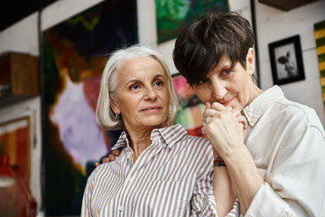 Two women stand side by side in an art studio.
