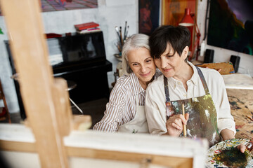 A mature lesbian couple sitting peacefully in an art studio.