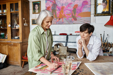 Two women happily painting together in a cozy studio.