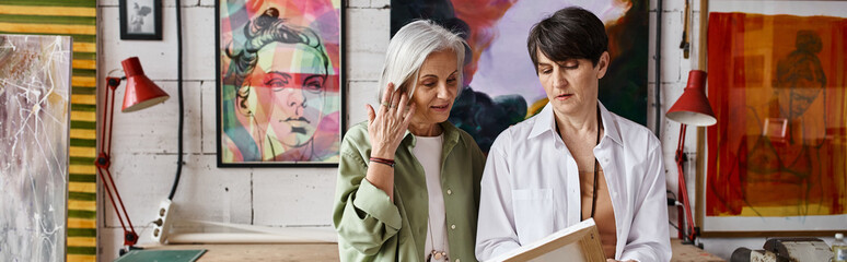 Two women admire paintings in a cozy room filled with art.