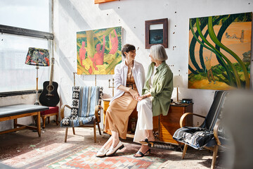 Mature lesbian couple engaged in conversation in an art studio.