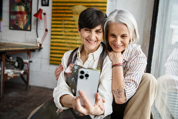 Two women joyfully taking a selfie with phone.